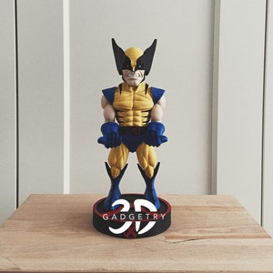 May include: A yellow and blue 3D printed figurine of Wolverine, a Marvel Comics superhero, with black claws and a black mask. The figurine is standing on a black base with the text "3D GADGETRY" printed on it.