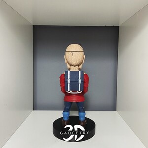 K&ouml;nnte beinhalten: Eine rote und blaue Figur eines Menschen mit einem Rucksack. Die Figur steht auf einem schwarzen Sockel mit dem aufgedruckten Text "3D GADGETRY".
