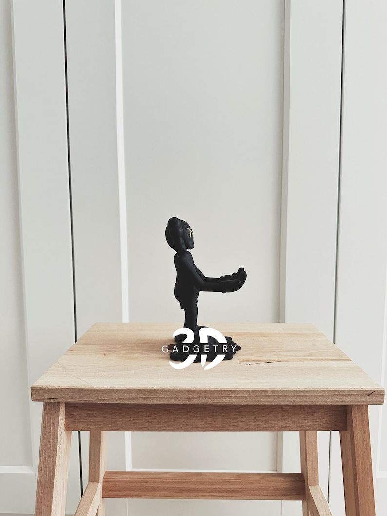 May include: Black figurine of a person with arms outstretched, standing on a wooden base with the text "3D GADGETRY".