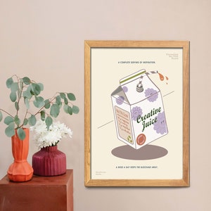 May include: A framed print featuring a cartoon illustration of a Creative Juice carton with a straw, purple flowers, and the text "Creative Juice." The print includes the text "A complete serving of inspiration" and "A dose a day keeps the blockage away."