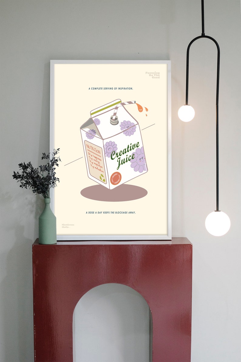 May include: A framed art print featuring a carton of "Creative Juice" with floral accents and a straw. The print includes the text "A complete serving of inspiration" and "A dose a day keeps the blockage away."