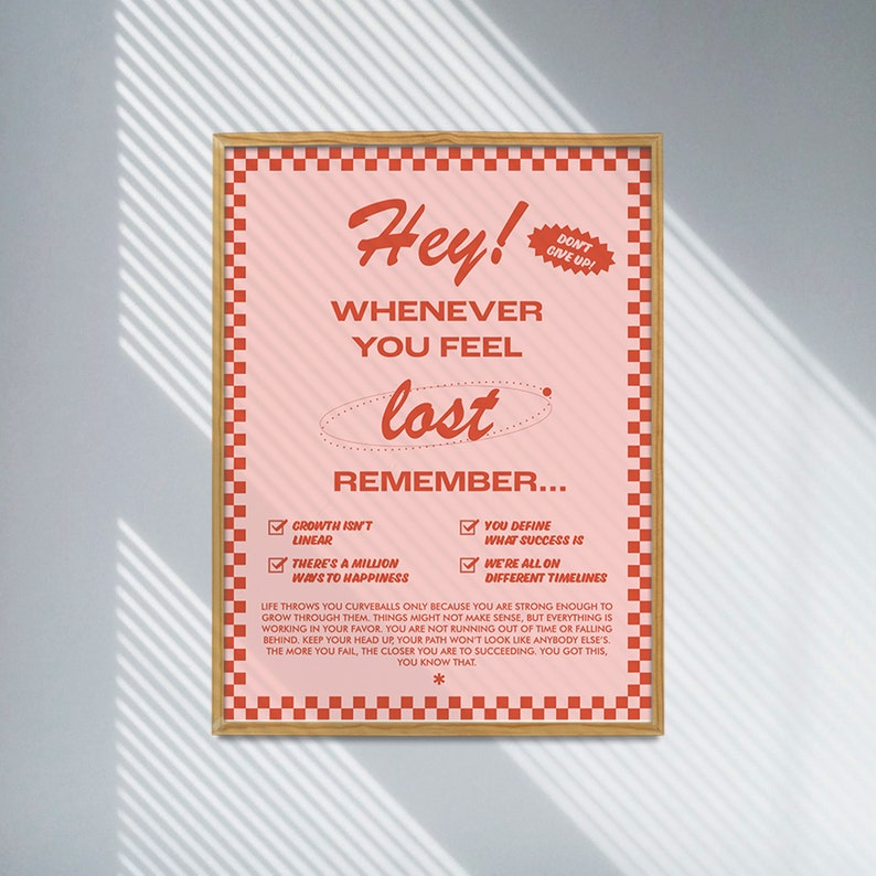 May include: A framed poster with a pink background and red text. The poster reads "Hey! Whenever you feel lost, remember..." with motivational phrases. The frame is a light brown color.