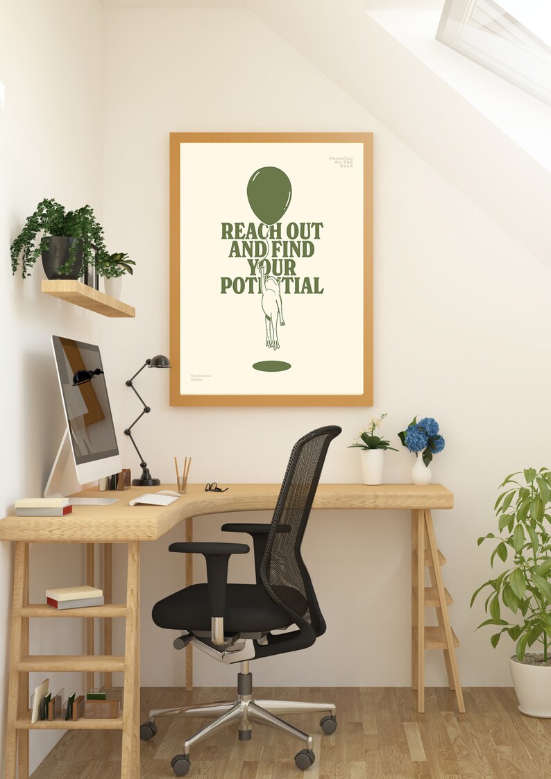Pu&ograve; includere: Un poster incorniciato con la scritta "REACH OUT AND FIND YOUR POTENTIAL" in verde, sopra un'illustrazione di una persona che raggiunge un palloncino. Il poster &egrave; in una cornice di legno chiaro, esposto in un ambiente di home office con una scrivania in legno e una sedia da ufficio nera.