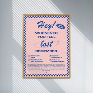 May include: Pink poster with blue text and a checkered border. The poster reads "Hey! Whenever you feel lost, remember..." followed by inspirational statements. A small blue sticker says "Don't Give Up!"