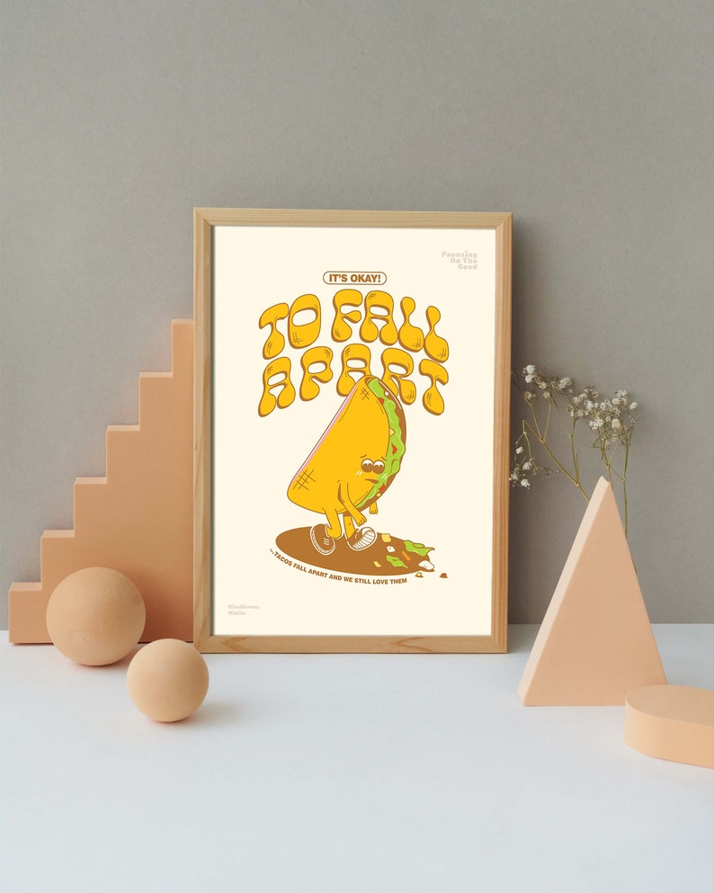 May include: A framed print featuring a cartoon taco character with the text "TO FALL APART" and "IT'S OKAY!". The taco is yellow with a green border, brown shoes, and a sad expression. The print is in a wooden frame.
