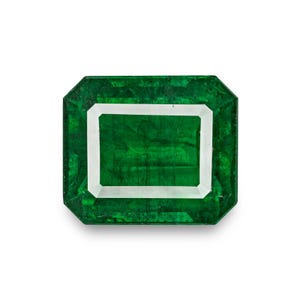 Pode incluir: Uma vibrante pedra preciosa de esmeralda com corte esmeralda. A gema é de cor verde profundo com uma borda branca, sobre um fundo branco. A esmeralda tem uma forma retangular com cantos cortados.