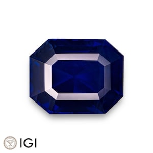 May include: A deep blue sapphire gemstone with a rectangular emerald cut. The gemstone is faceted and has a high polish.