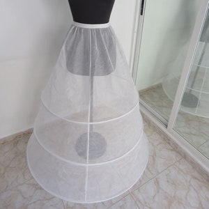 May include: A white tulle petticoat with three layers and a satin waistband. The petticoat is on a dress form.