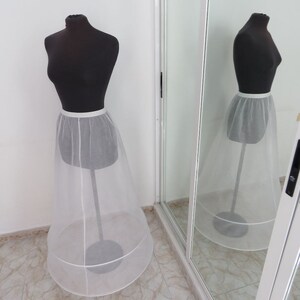 May include: A white tulle petticoat with a satin waistband. The petticoat is on a mannequin and is displayed against a white background.