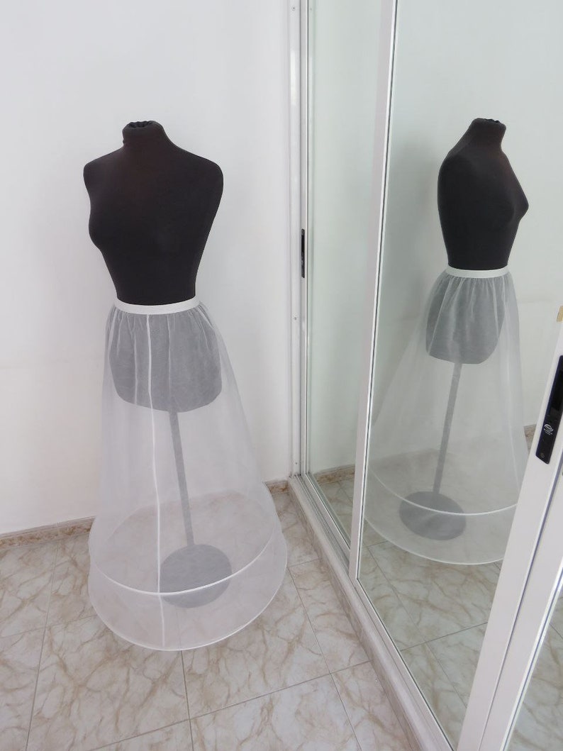 May include: A white tulle petticoat with a satin waistband. The petticoat is on a mannequin and is displayed against a white background.