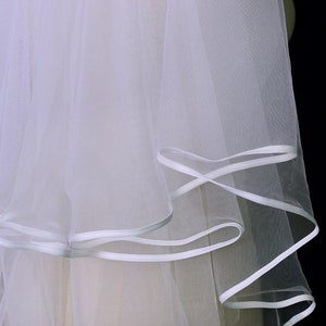 Back view of a long cathedral veil with two layers over a white wedding gown.