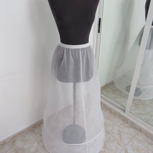 May include: A white tulle petticoat with a satin waistband. The petticoat has two layers of tulle and a circular shape.