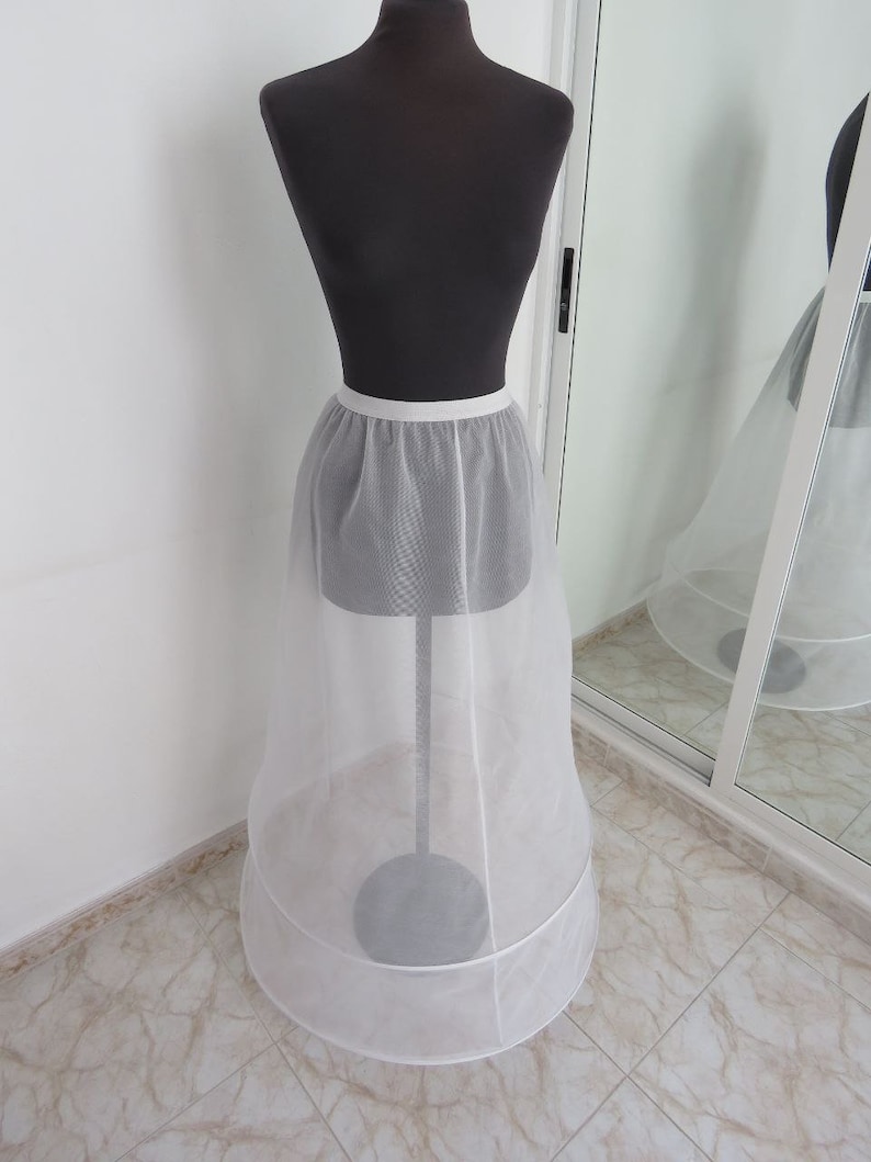 May include: A white tulle petticoat with a satin waistband. The petticoat has two layers of tulle and a circular shape.