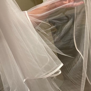 Bride wearing a two-tier cathedral wedding veil with a blusher and satin ribbon edge.