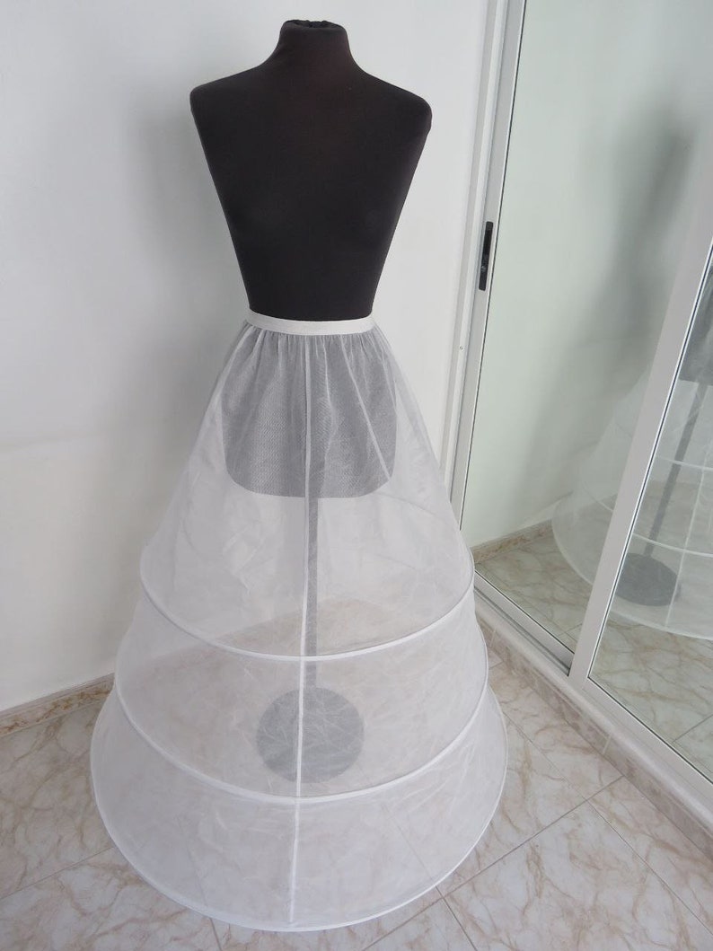 May include: A white tulle petticoat with three layers and a satin waistband. The petticoat is on a dress form.