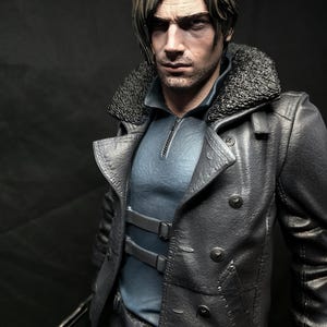 May include: A detailed figurine of a man with short, styled hair and a stern expression. He wears a dark gray leather coat with a fur collar over a blue shirt. The figure holds a weapon with a blood-like substance on it.
