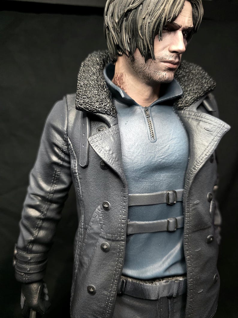 May include: A detailed figurine of a man with short, light brown hair and a serious expression. He wears a gray coat with a faux fur collar, a light blue shirt, and black gloves. The coat has multiple buttons and straps.