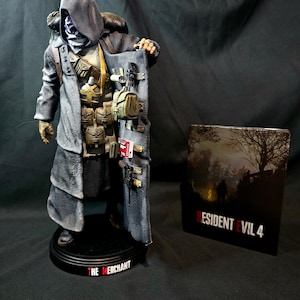 May include: A detailed figurine of the Merchant from Resident Evil 4, wearing a hooded cloak and holding a variety of weapons and items. The figurine is standing on a black base with the words "The Merchant" printed on it. The image also includes a Resident Evil 4 game case.