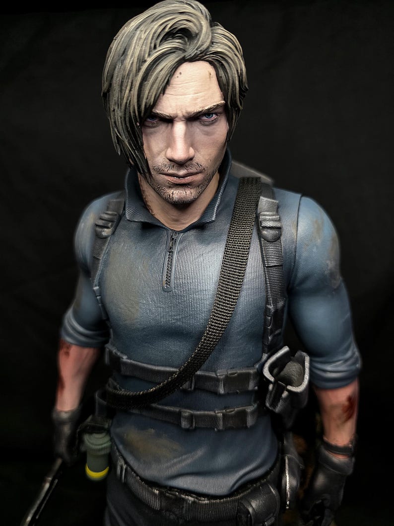 May include: A detailed figurine of a man with short, styled, light brown hair and a stern expression. He wears a blue tactical shirt with a black harness and utility belt. The figure has a realistic, weathered appearance, with visible details like a holster and a small grenade.