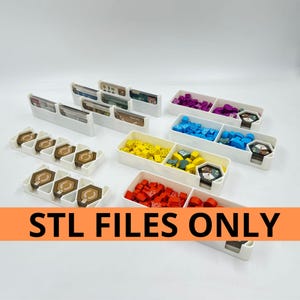 Op de afbeelding: Witte plastic spelorganizers gevuld met kleurrijke spelstukken en kaarten. De organizers zijn verdeeld in compartimenten, met rode, gele, blauwe en paarse spelcomponenten. Tekst op een oranje banner: "STL FILES ONLY."