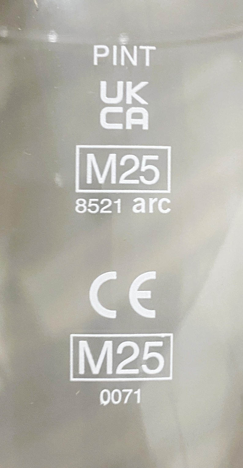 May include: Close-up of a silver surface with the word "PINT" at the top, followed by "UK" and "CA". Below are the markings "M25" and "8521 arc". The CE mark and "M25" are at the bottom, with the number "0071".