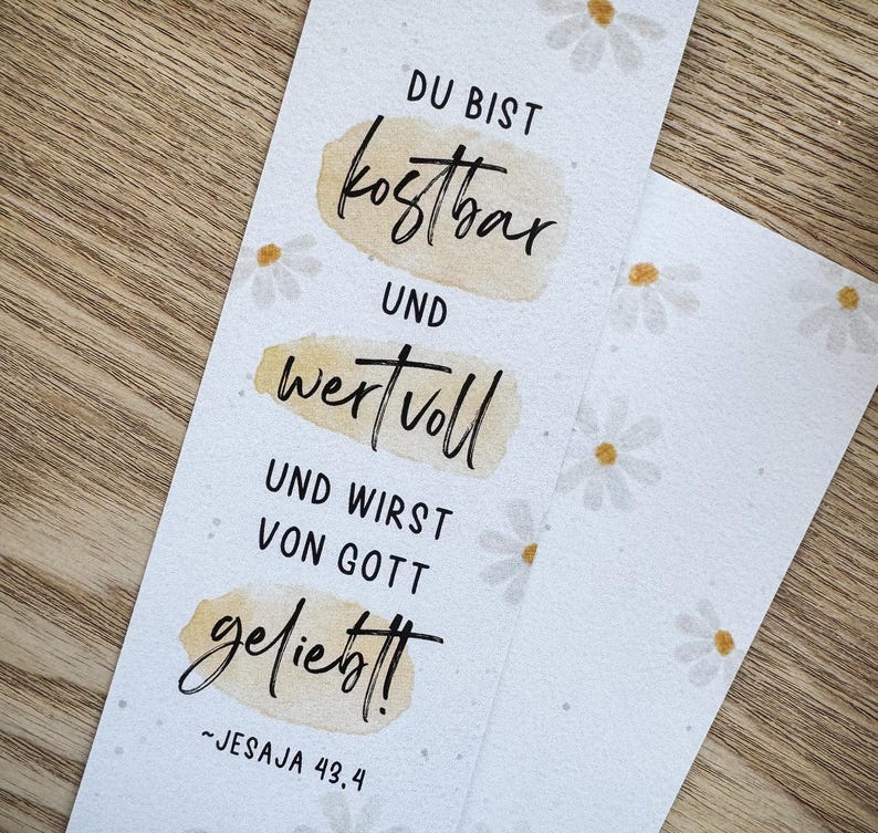 K&ouml;nnte beinhalten: Wei&szlig;er Lesezeichen mit G&auml;nsebl&uuml;mchenmuster und Text auf Deutsch: "DU BIST kostbar UND wertvoll UND WIRST VON GOTT geliebt!" (Du bist kostbar und wertvoll und geliebt von Gott). Inklusive Bibelvers Jesaja 43,4.