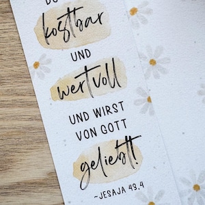 K&ouml;nnte beinhalten: Zwei wei&szlig;e Lesezeichen mit G&auml;nsebl&uuml;mchenmustern und deutschem Text. Der Text lautet "DU BIST kostbar UND wertvoll UND WIRST VON GOTT geliebt!" mit dem Verweis "~JESAJA 43,4". Der Text ist in schwarzer Schrift auf beigefarbenen Aquarellflecken.