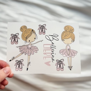 Könnte beinhalten: Eine weiße Karte mit Illustrationen von zwei Ballerinas mit blonden Haaren und rosa Tutus, umgeben von rosa Ballettschuhen. Die Karte zeigt den Text "Ballerina Liebe" in schwarzer Schrift und rosa Buchstaben, mit einem rosa Herz.