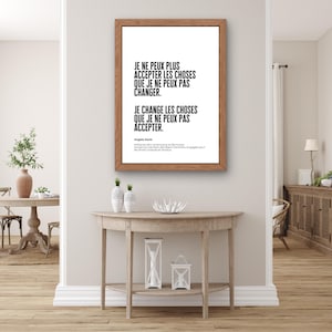 Può includere: Una stampa incorniciata con cornice in legno mostra una citazione in testo nero su sfondo bianco. La citazione recita: "JE NE PEUX PLUS ACCEPTER LES CHOSES QUE JE NE PEUX PAS CHANGER. JE CHANGE LES CHOSES QUE JE NE PEUX PAS ACCEPTER." L'autore è Angela Davis.