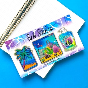 May include: A sticker sheet featuring three distinct designs: a palm tree in a window frame, an aquarium scene with a treasure chest, and a bottle of soap with a fish inside. The text "Pack Stickers" and "ihoomiart-shop.com" is printed on the sheet.