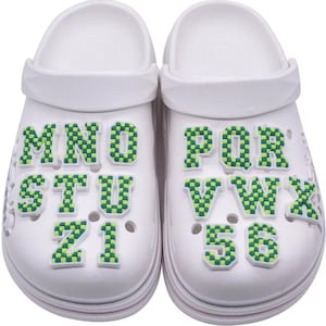 May include: White clogs with green and yellow checkered alphabet letter charms. The letters on the left clog are MNO, STU, and Z1. The letters on the right clog are PQR, VWX, and 56.