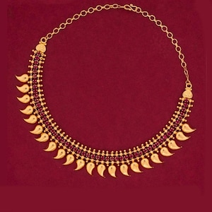 May include: Gold-toned necklace with a series of small, round, red gemstones set in a row. The necklace features a chain and is adorned with gold teardrop-shaped pendants. The background is a solid, deep red.