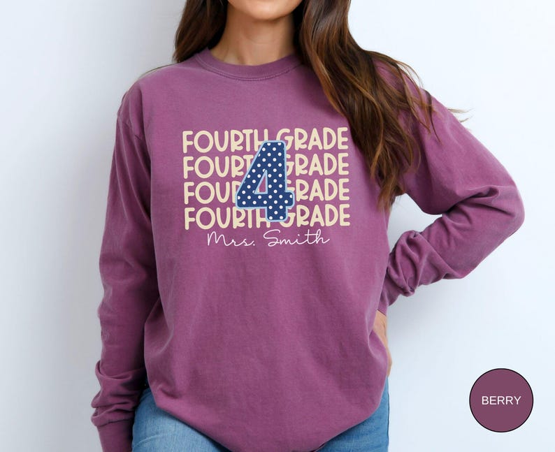 May include: A berry-colored long-sleeve sweatshirt featuring the text FOURTH GRADE repeated in a light cream color. A large navy blue number 4 with white polka dots is centered over the text. Below, the name Mrs. Smith is printed in white script.