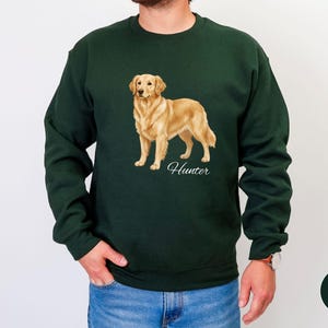 May include: Forest green sweatshirt featuring a golden retriever illustration. The dog is standing, with the name "Hunter" in script below. The sweatshirt is a solid color, with a crew neck and long sleeves.