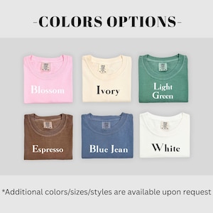 Op de afbeelding: Een afbeelding met zes opgevouwen t-shirts in verschillende kleuren: roze, cr&egrave;me, groen, bruin, blauw en wit. Elk shirt is gelabeld met zijn kleurnaam: Blossom, Ivory, Light Green, Espresso, Blue Jean en White. De tekst "COLORS OPTIONS" staat bovenaan.