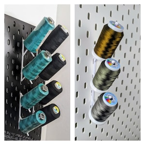 May include: Two different types of thread organisers. The first is a wall-mounted rack with six spools of thread in various colours. The second is a freestanding rack with four spools of thread in different colours.