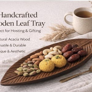 May include: A white ceramic mug with a black handle and the text "But First, Coffee" in a bold, black font. The mug is set against a blurred background, suggesting a cozy setting.