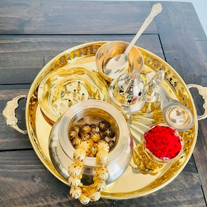 May include: A gold metal tray with handles, containing various bowls and a spoon. The tray is filled with small gold beads, red powder, and other items.