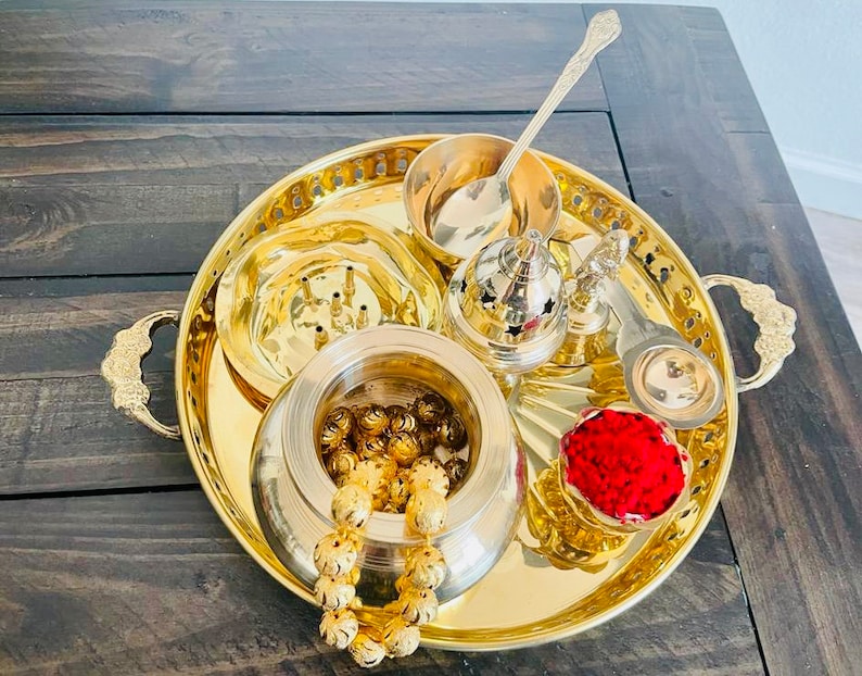 May include: A gold metal tray with handles, containing various bowls and a spoon. The tray is filled with small gold beads, red powder, and other items.