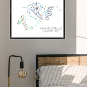 Op de afbeelding: Een zwart ingelijste print van een skigebied met de tekst "Smugglers' Notch Vermont | USA".