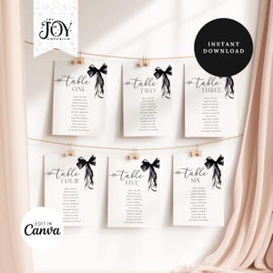 Può includere: Sei carte da tavolo da matrimonio stampabili con fiocchi ad acquerello neri e i numeri da tavolo da uno a sei. Le carte sono appese a una corda con mollette.