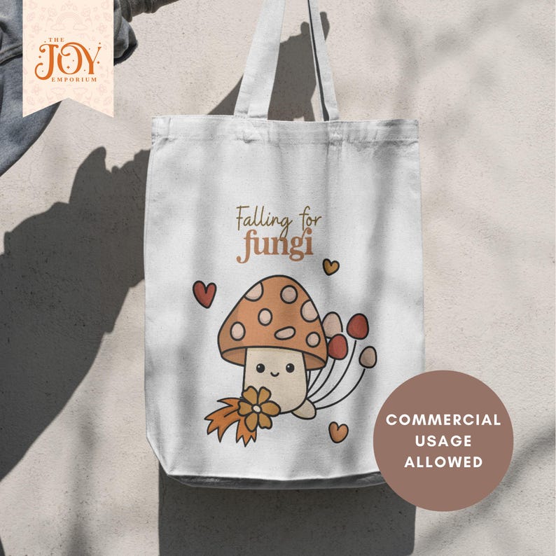 Op de afbeelding: Witte draagtas met een cartoon paddenstoel ontwerp en de tekst "Falling for fungi". De paddenstoel heeft een bruine kap met witte stippen, een lachend gezicht en is omringd door harten en andere paddenstoelen. De tas heeft een stempel "Commercial Usage Allowed".