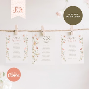 Può includere: Tre segnaposto per matrimoni con disegni floreali e nomi degli invitati, appesi a uno spago con mollette di legno. Le carte hanno il testo "Table One", "Table Two" e "Table Three". L'immagine include anche il testo "Instant Download" e "Edit in Canva".