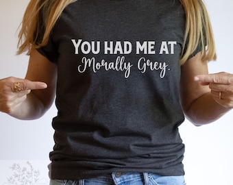 May include: A dark grey t-shirt with the text "You had me at morally grey." printed in white.