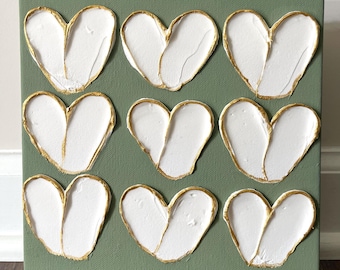 May include: A square canvas painting with nine white hearts outlined in gold on a sage green background.