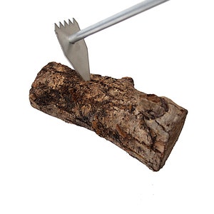 May include: A metal tool with a pointed end is being used to split a log of wood.