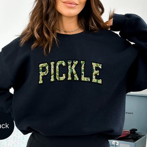 a woman wearing a black sweatshirt with the word pickle printed on it