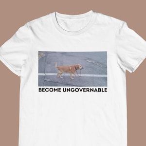 Może przedstawiać: Biała koszulka z nadrukiem zdjęcia psa idącego chodnikiem i tekstem "Become Ungovernable" umieszczonym pod zdjęciem.