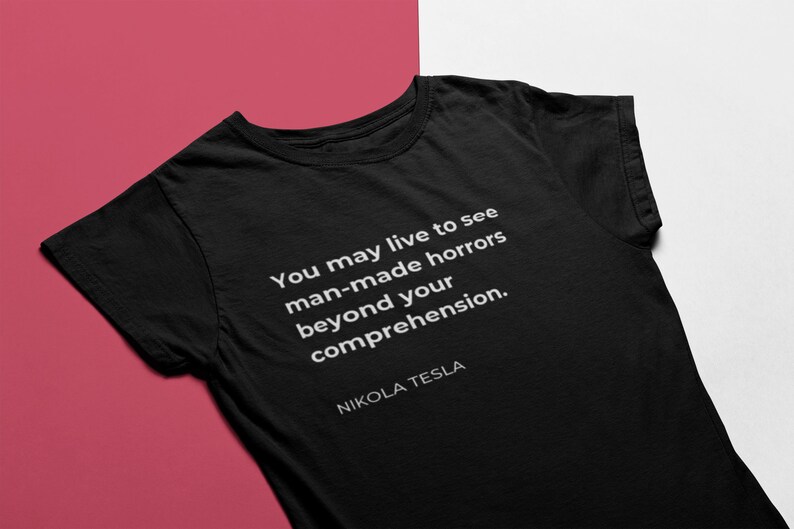 May include: Black t-shirt with a white quote that reads "You may live to see man-made horrors beyond your comprehension." The quote is attributed to Nikola Tesla.