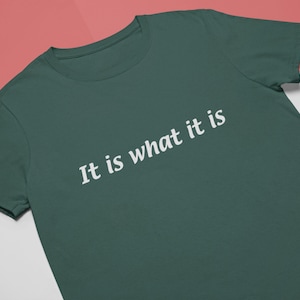 K&ouml;nnte beinhalten: Ein dunkelgr&uuml;nes T-Shirt mit dem Aufdruck "It is what it is" in wei&szlig;.